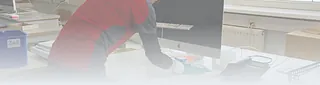 Person in rotem Pullover arbeitet am Schreibtisch mit Computer im Büro